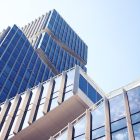 Low-angle shot of a modern skyscraper with reflective glass design under a clear blue sky.