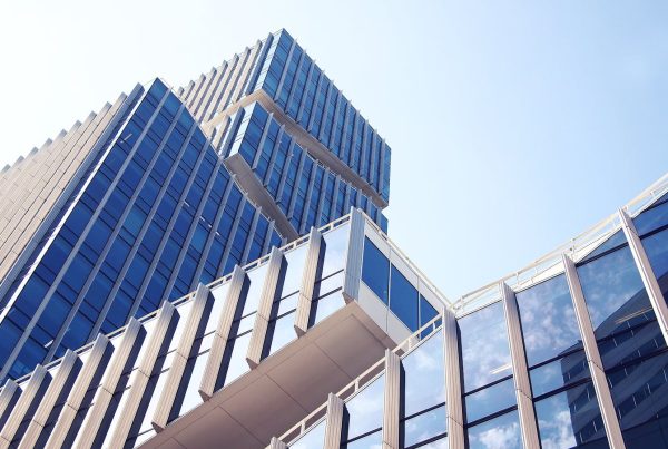 Low-angle shot of a modern skyscraper with reflective glass design under a clear blue sky.