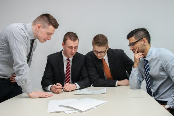 four men looking to the paper on table