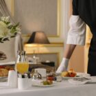 A luxurious hotel room showcasing an elegant room service breakfast setup with fresh flowers and a platter of assorted pastries.