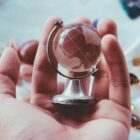 person holding gray metal framed desk globe paper weight