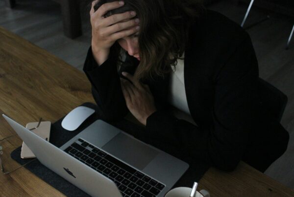 stressed woman with head in hands at laptop